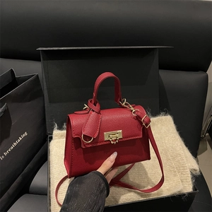 Elegant red pebbled leather handbag with gold hardware displayed in a luxury gift box