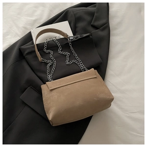 Gros plan d'un sac en daim marron sur un blazer noir avec détail de chaîne argentée