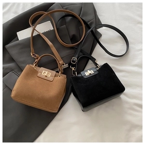 Detail of brown and black mini square bags with gold twist locks on grey blazer
