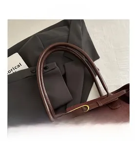 Detailed close-up of dark brown suede tote bag featuring premium leather handle and gold buckle