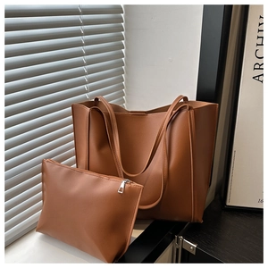 Detailed view of brown leather tote bag set with matching inner pouch in natural light