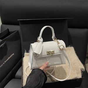Elegant white litchi pattern handbag with gold clasp on a luxury gift box display