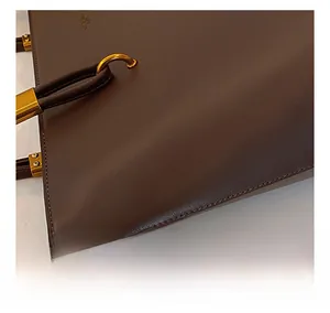 Close-up of brown PU leather tote bag showing fine stitching and gold metal buckle