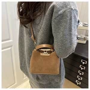 Close-up of brown suede mini crossbody bag with gold twist lock and adjustable strap