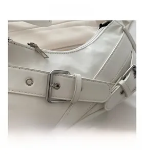 Detailed close-up of white leather baguette bag featuring silver metal buckle and zipper