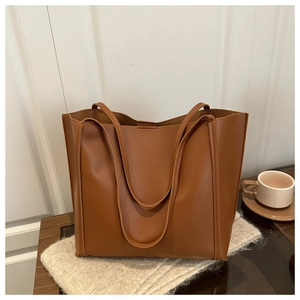Caramel brown matte faux leather tote bag on wooden table with a coffee cup