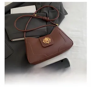 Detailed view of brown leather bag with gold buckle next to a phone for size comparison
