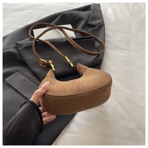 Détail du sac bandoulière croissant en daim marron avec ferrures dorées polies