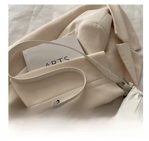 Detail of creamy white leather baguette bag with silver hardware on a minimal background