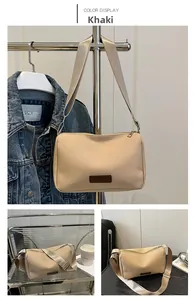 Detail view of khaki crossbody bag with leather fashion tag and adjustable strap