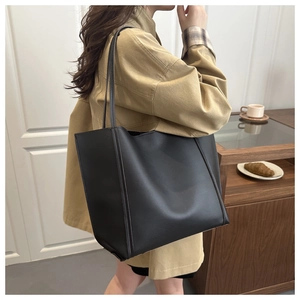 Detailed side view of a large black leather tote bag worn on shoulder for commuting