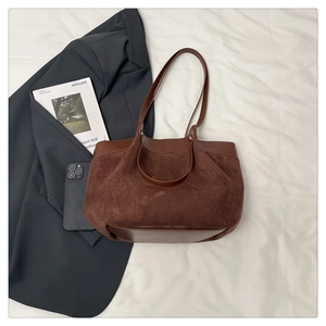 Vue détaillée d'un sac cabas en daim marron avec bordures en cuir sur tissu blanc