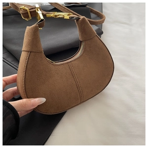 Détail du sac à main croissant en daim marron avec fermoir doré et couture centrale