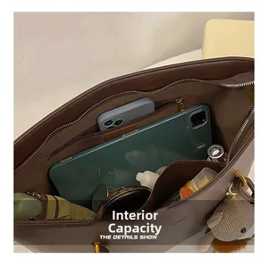 Detailed interior of a brown leather tote bag showing large capacity for laptop and daily items
