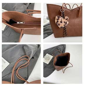 Detail view of brown pebbled leather tote bag with metal zipper and leopard heart charm