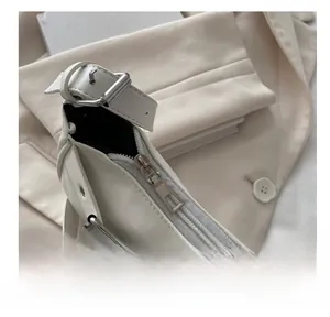 Close-up of smooth silver metal zipper and white leather texture on baguette bag