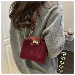 Detail of burgundy crossbody bag featuring matte suede texture and gold twist lock closure