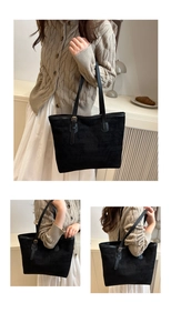 Detail view of large black faux suede tote bag featuring slim leather straps and metal buckle