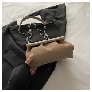Détail d'un sac plissé en daim kaki avec bandoulière chaîne sur un blazer noir
