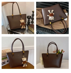 Detail of dark brown faux leather tote bag with plush bear charm and gold logo accent