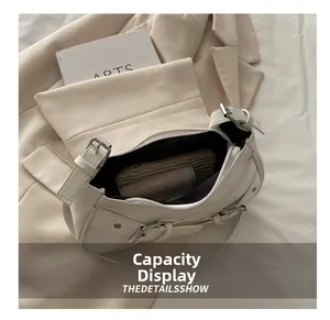 Detail showing internal capacity of the white baguette bag with faux leather buckle straps