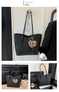 Detail of black pebbled leather tote bag with heart leopard plush charm for work