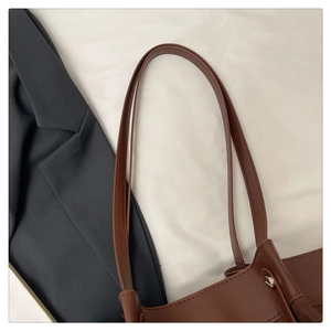 Détail d'un sac cabas en cuir marron avec coutures fines sur texture lisse et anses solides