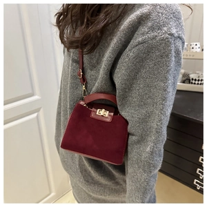 Detail of burgundy suede tote with gold twist lock and smooth leather handle trim