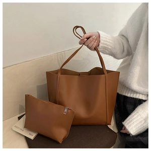 Detail of a brown leather tote bag with a matching small zipper pouch in a hand-held setting