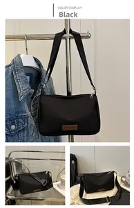 Detail of water-resistant black crossbody bag with adjustable strap and fashion patch