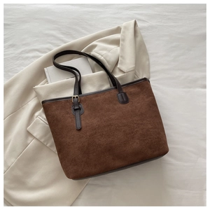 Detail of dark brown suede tote bag featuring leather trim and golden metal buckle