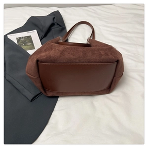 Gros plan détaillé des coutures en daim et cuir marron foncé sur un grand sac cabas