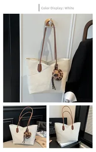 Detail of off-white lychee leather tote bag with V-stitch and leopard print charm
