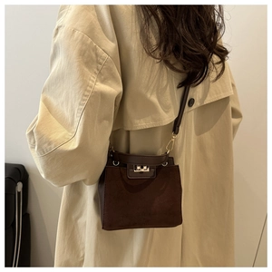 Close-up of small brown retro shoulder bag with silver twist-lock and suede texture