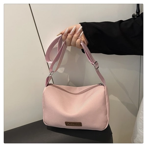 Détail du sac bandoulière en toile rose imperméable avec sangle réglable et plaque logo