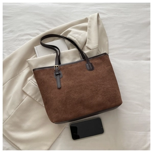Detail shot of large brown suede tote bag showing interior capacity with a book and phone