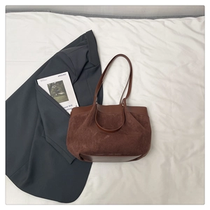 Détail d'un sac cabas en daim marron foncé avec finitions en cuir lisse et fines lanières