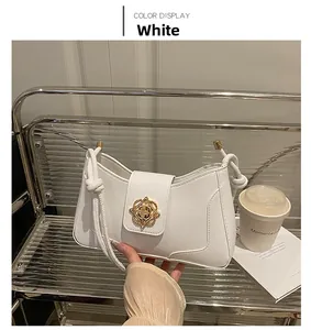 Detail of white leather shoulder bag with gold flower buckle and knot shoulder strap