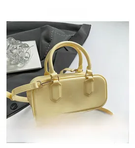 Close-up of cream yellow glossy patent leather handbag with gold-tone hardware and strap