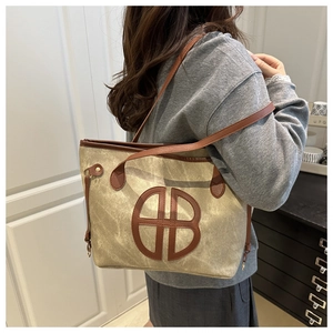 Detail of canvas tote bag showing brown leather logo patch and adjustable shoulder straps