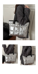 Detail of silver metallic quilted tote bag with black wide straps and textured sewing