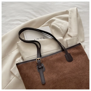 Detail of dark brown corduroy tote bag showing textured fabric and leather strap