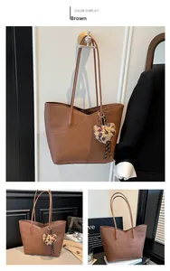 Detail of brown litchi pattern leather tote bag with V-shaped top and leopard heart charm