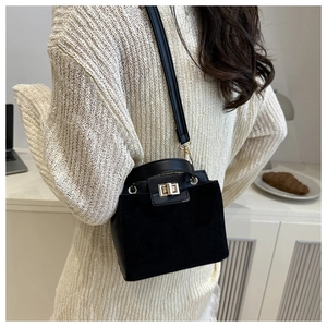 Close-up of black suede and leather crossbody bag with gold square turn-lock closure