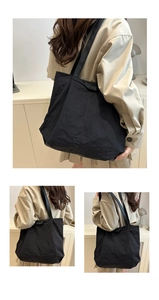 Detail of black nylon tote bag featuring fashion label and textured wrinkle finish