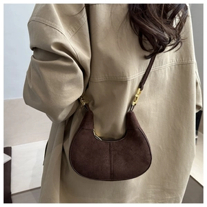 Détail du sac croissant en daim marron foncé avec ferrures dorées sur modèle