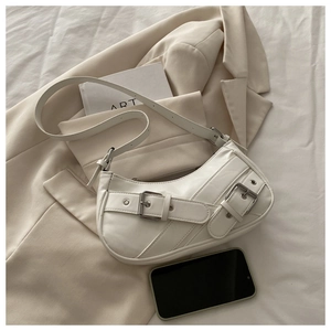 Detail view of white crescent shoulder bag with parallel buckle straps and silver hardware
