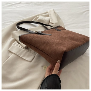 Detail of suede and leather textures on a brown large-capacity tote bag with metal buckle