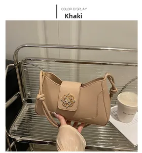 Detail of khaki leather shoulder bag featuring a gold floral clasp and knotted strap design