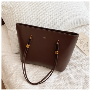 Close-up of brown PU leather tote bag with gold logo and vintage hardware detail